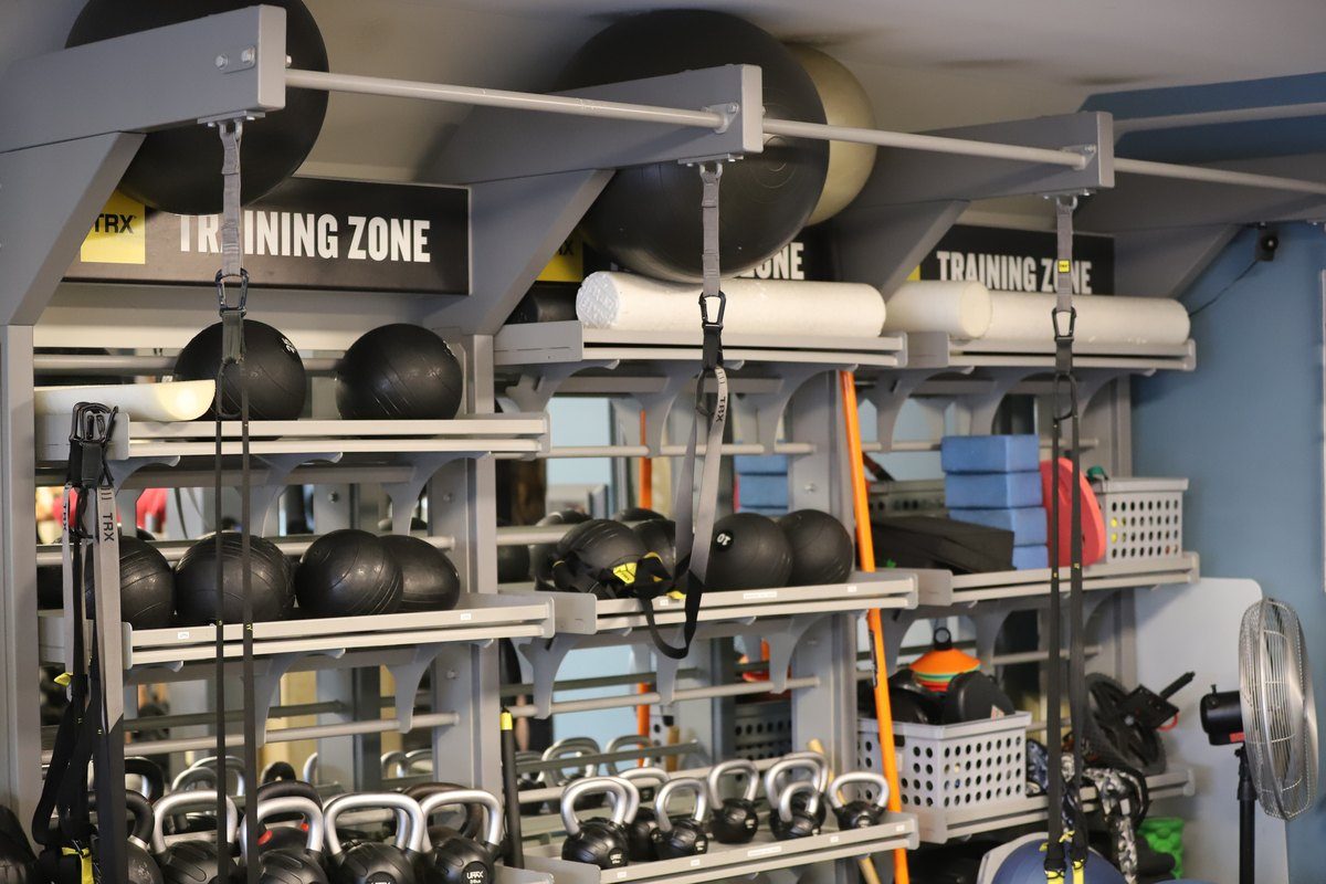 Fully equipped training floor — kettlebells, medicine balls, TRX, and mobility tools