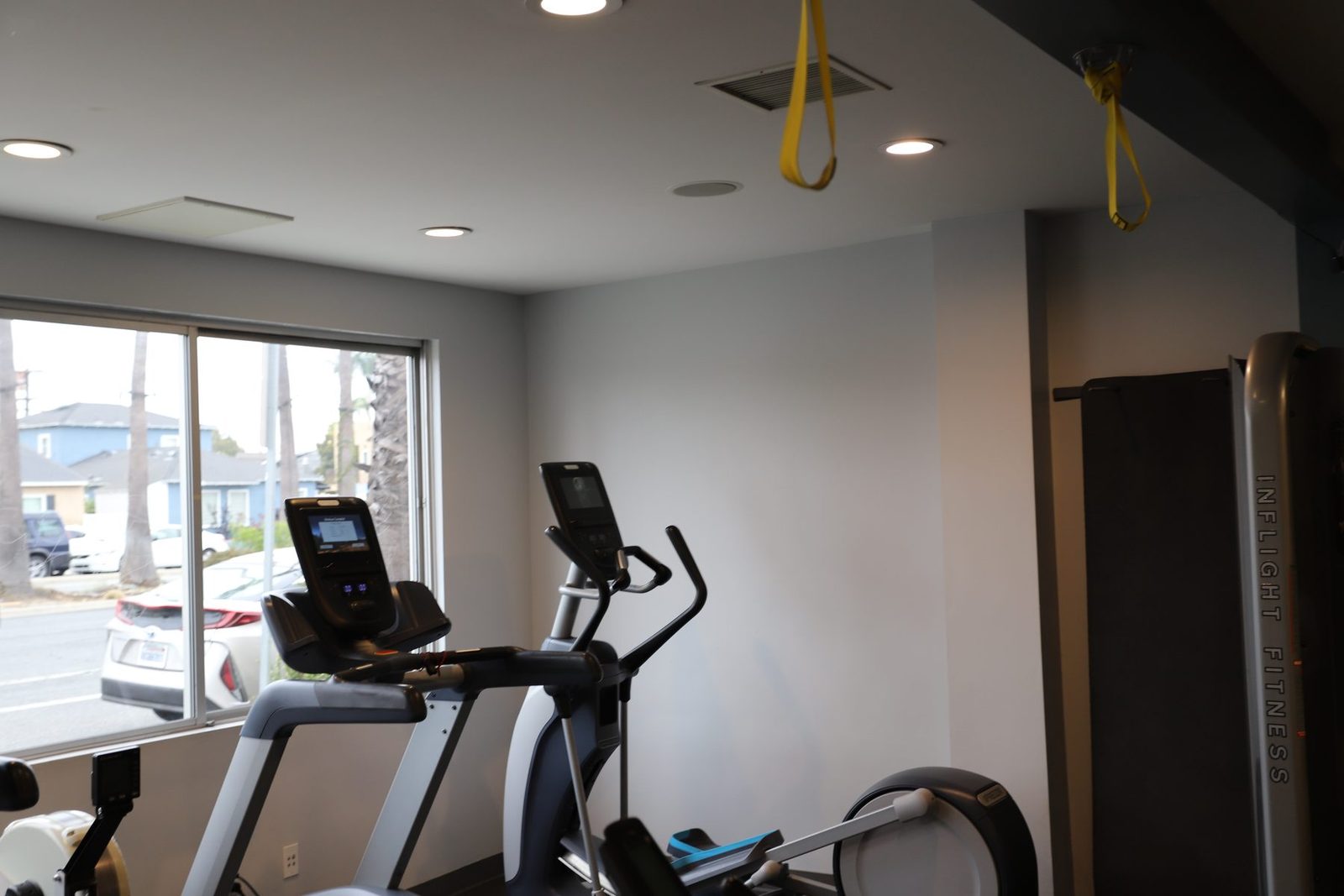 Cardio room — treadmill, elliptical, rower lit by a bright window