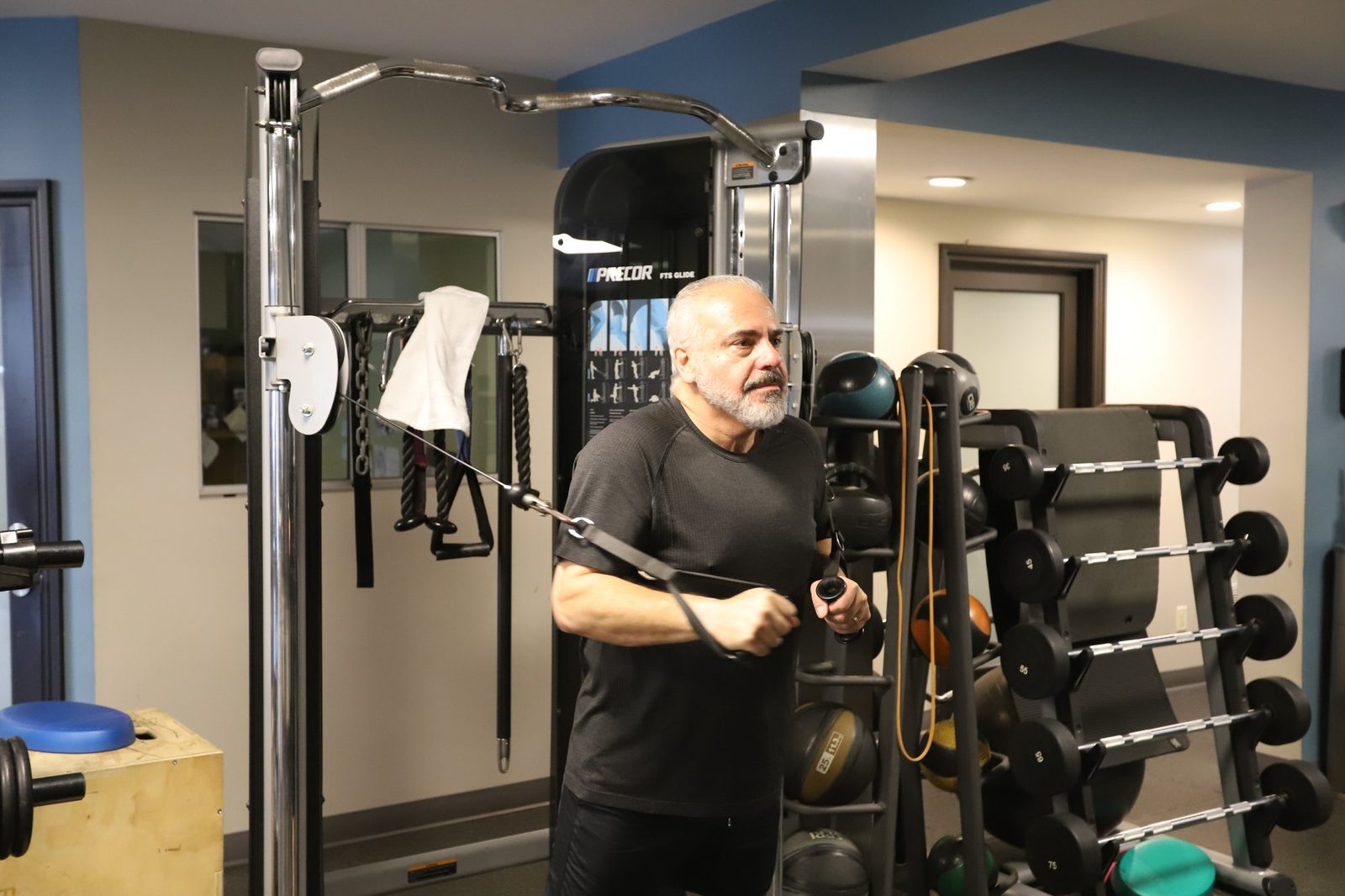An executive-age client training one-on-one on the cable machine at Executive Fitness